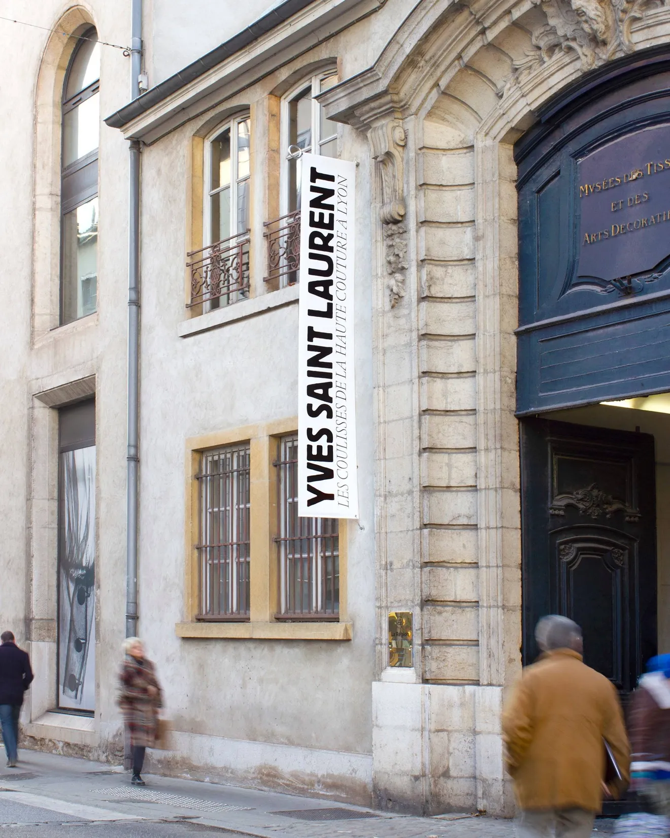 Bannières signalétiques en situation rue sur la façade du Musée des Tissus de Lyon — design de communication extérieure pour musée, graphiste freelance Cahors, Occitanie