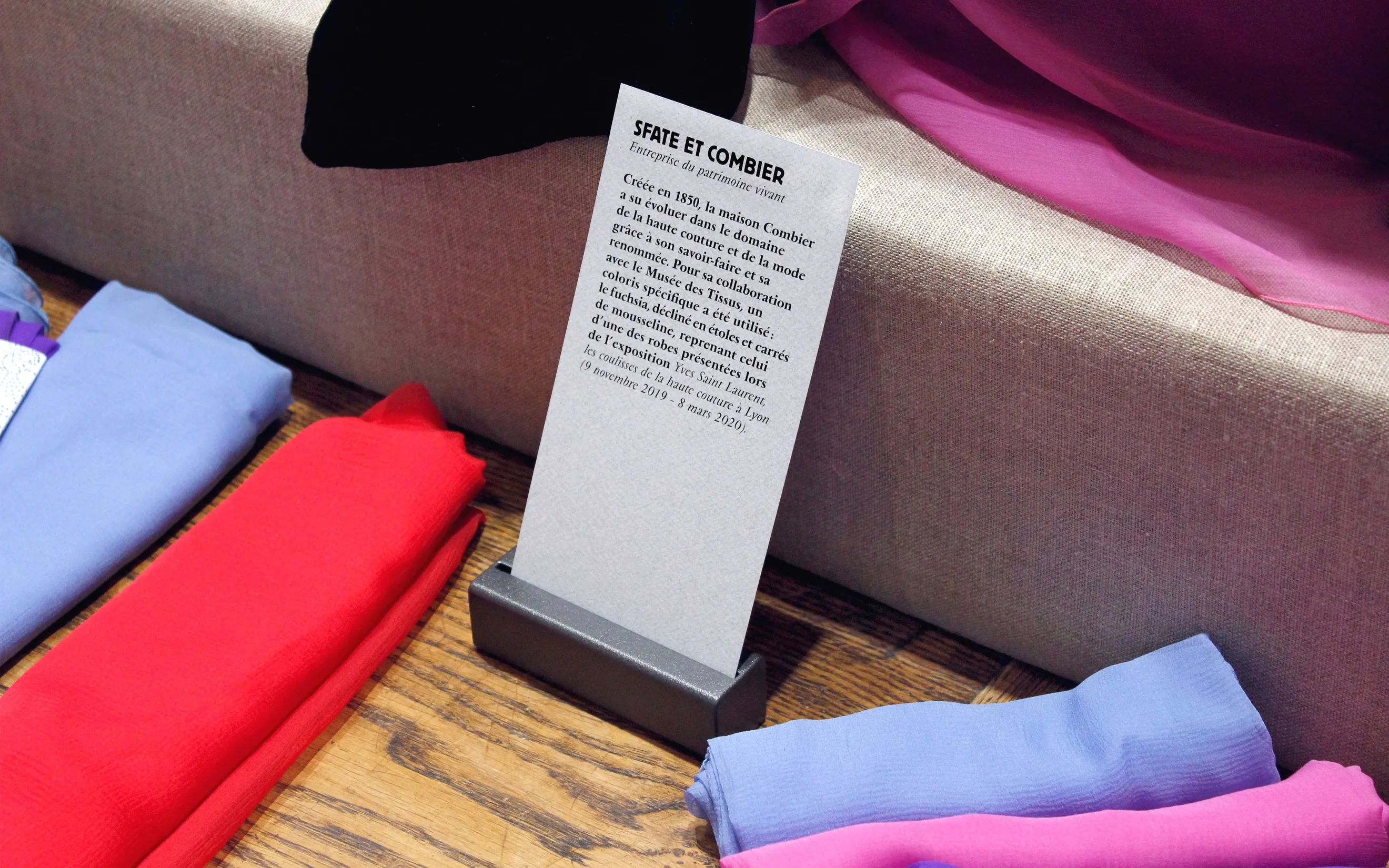 Présentoir avec étiquettes signalétiques et rouleaux de tissus au Musée des Tissus de Lyon — conception graphique de supports d'exposition pour musée textile, graphiste freelance Toulouse, Occitanie